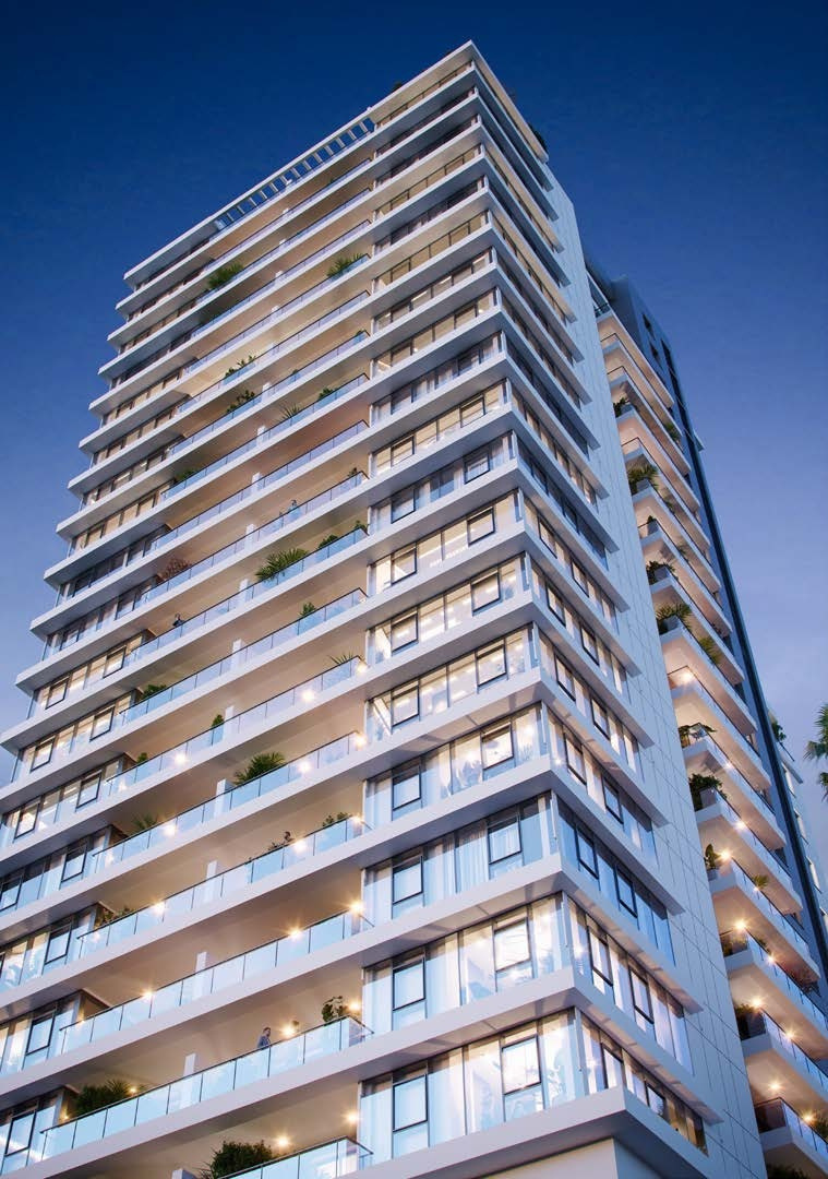 A tall, modern high-rise building in Netanya, Israel, featuring sleek glass balconies and a contemporary facade. The building is illuminated at dusk, showcasing its luxurious apartments and lush greenery on the balconies.