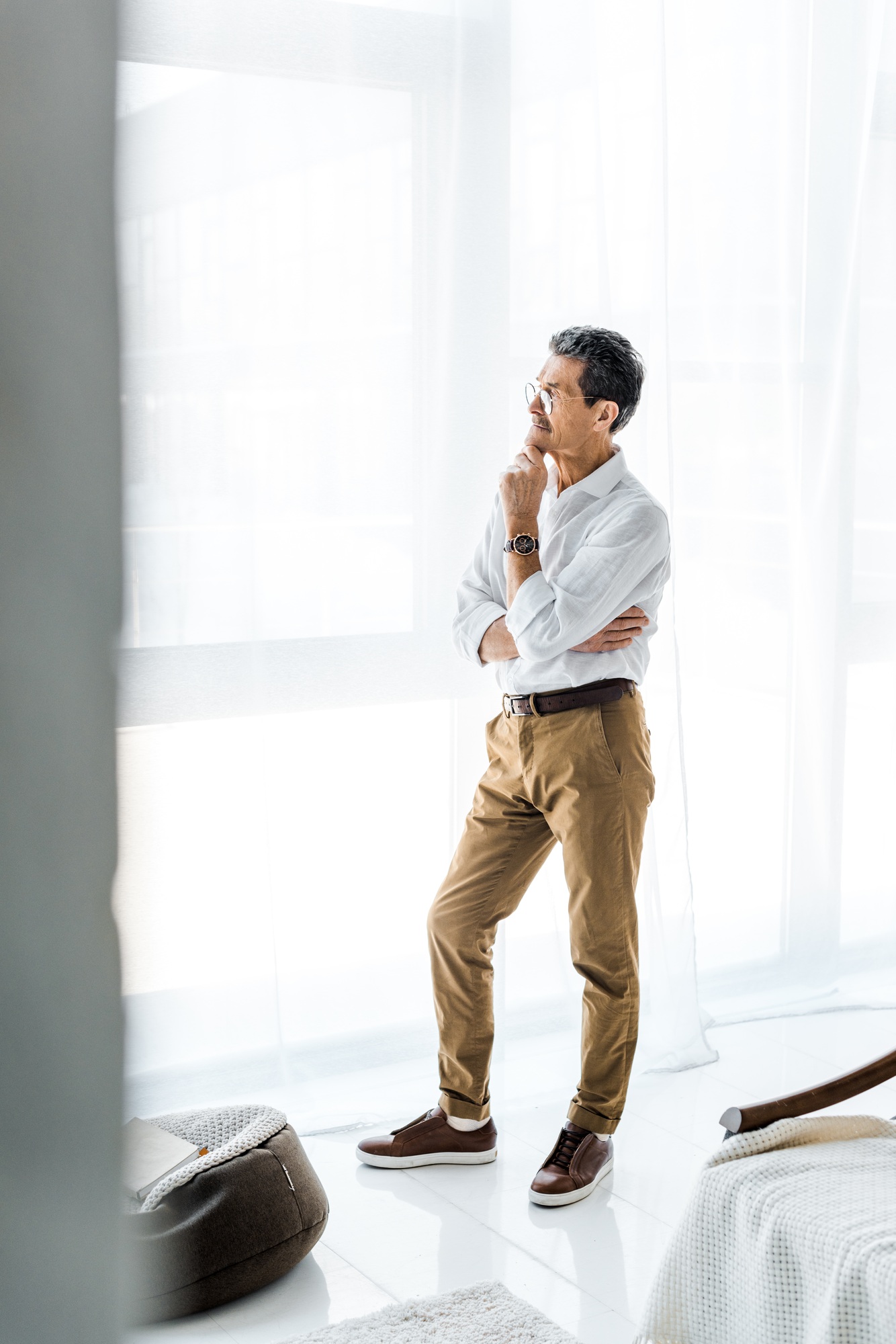 pensive senior man standing and thinking in modern home