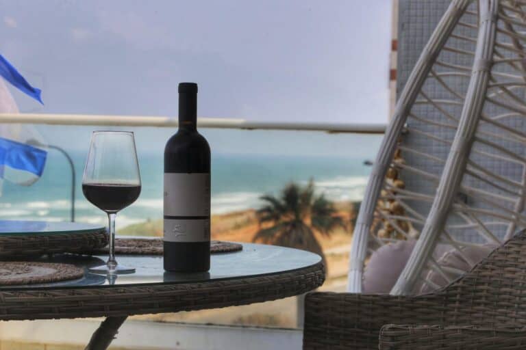 red wine bottle and glass on a beachside balcony