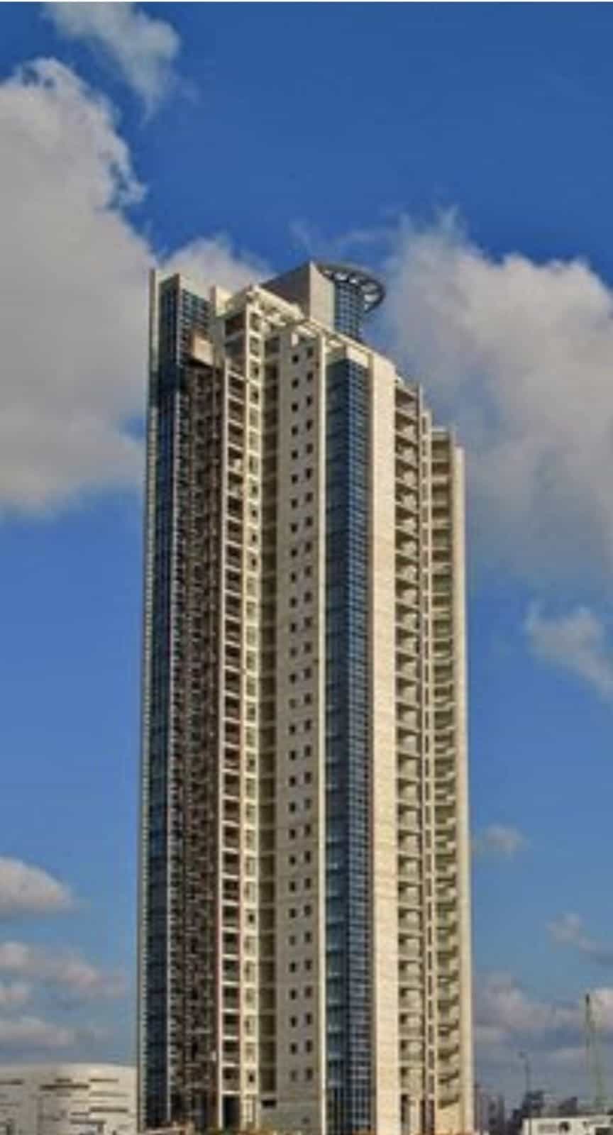 Tall building with blue windows and balconies visible.