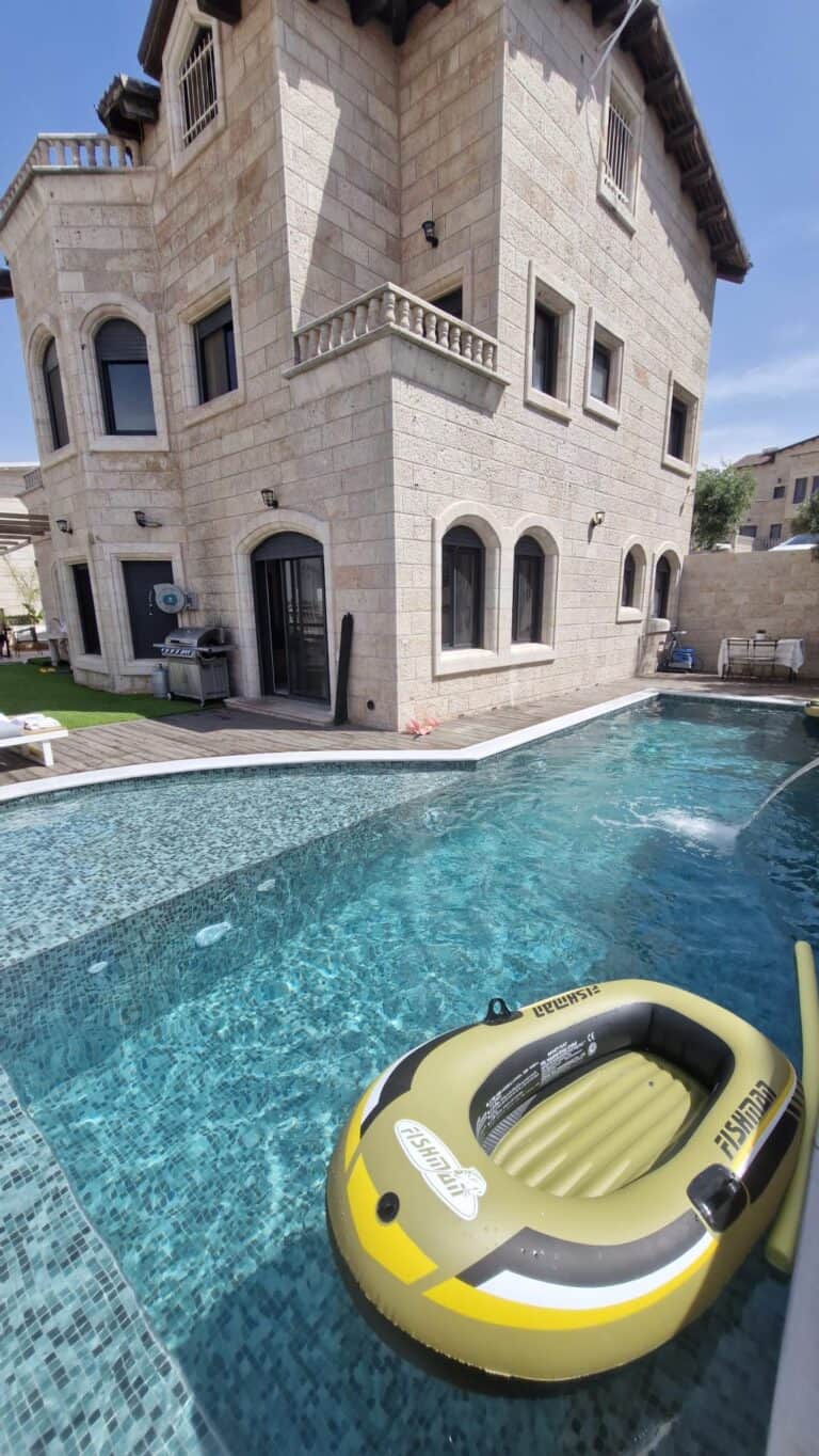 Luxurious villa pool with inflatable raft and stone exterior.