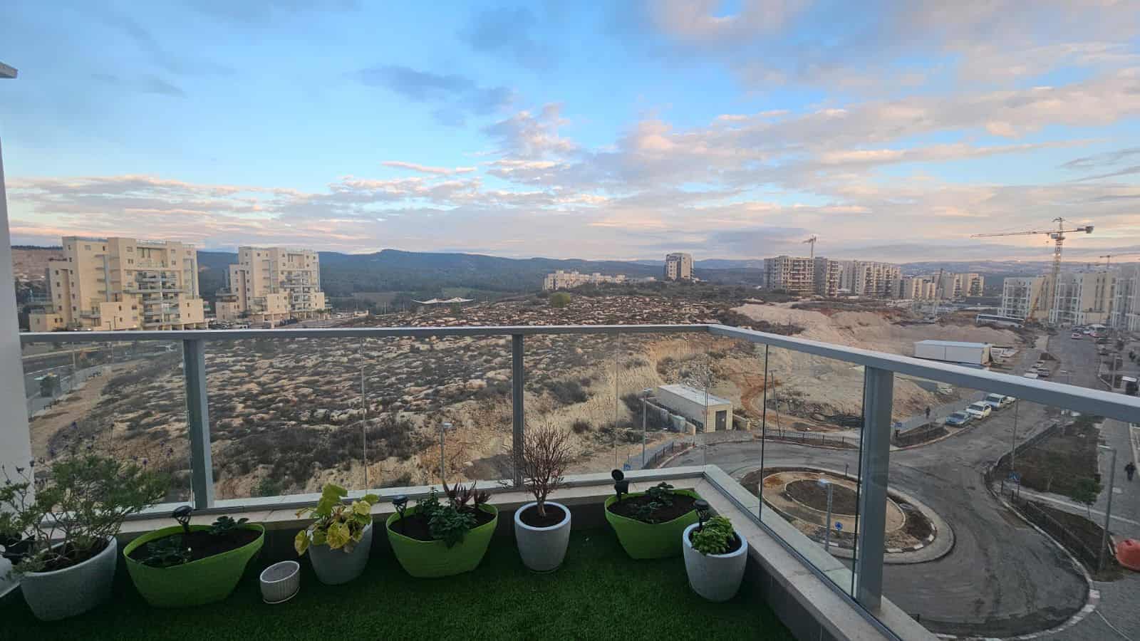 Balcony with plants overlooking city and construction site.