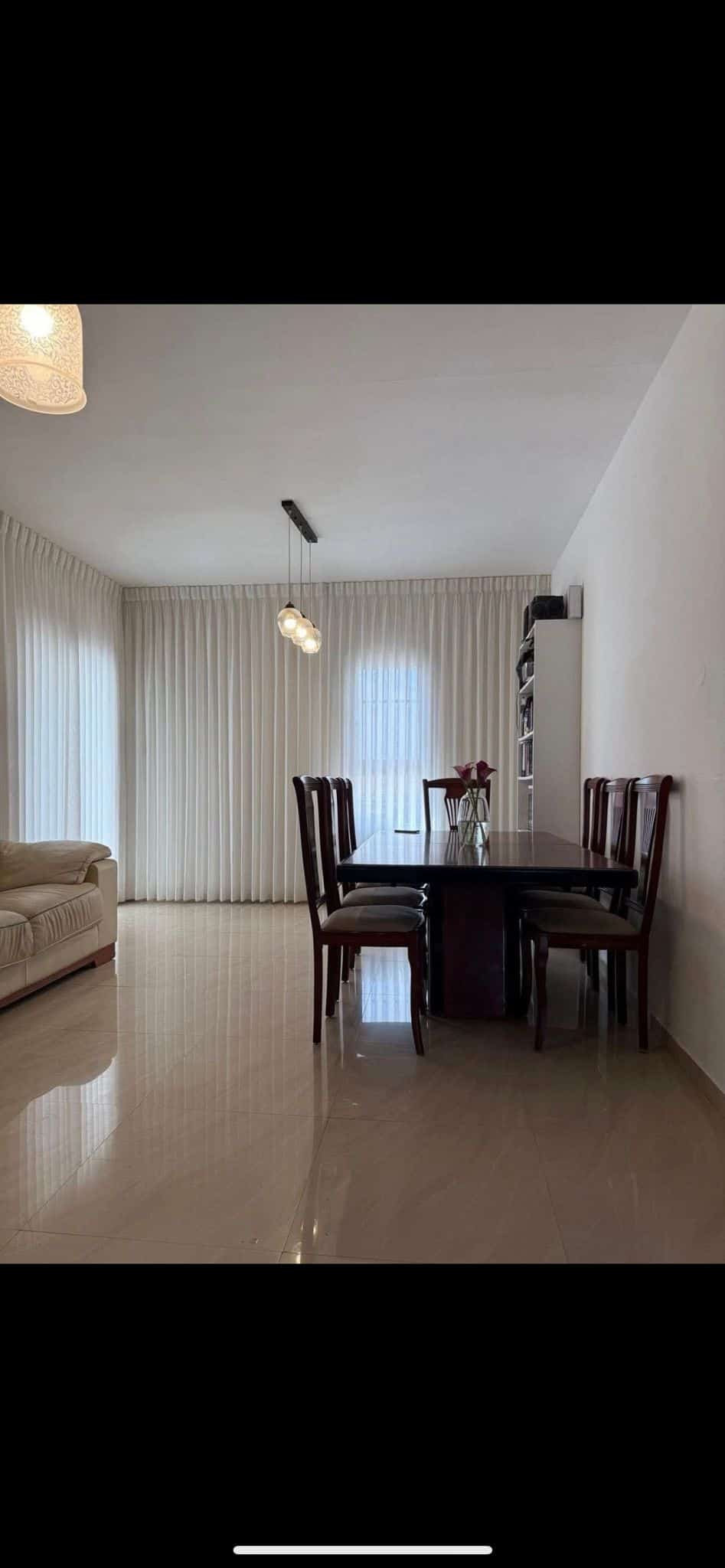 Dark wood dining table with chairs and white walls.