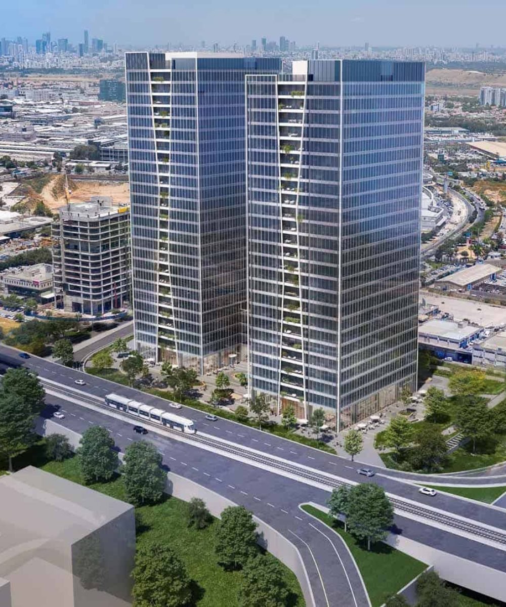 An aerial view of a cityscape with tall glass and steel buildings, a highway, and greenery.
