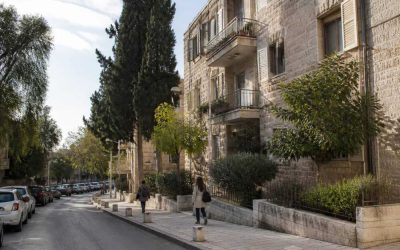 Residential street in Baka, Jerusalem with stone apartment buildings and pedestrians