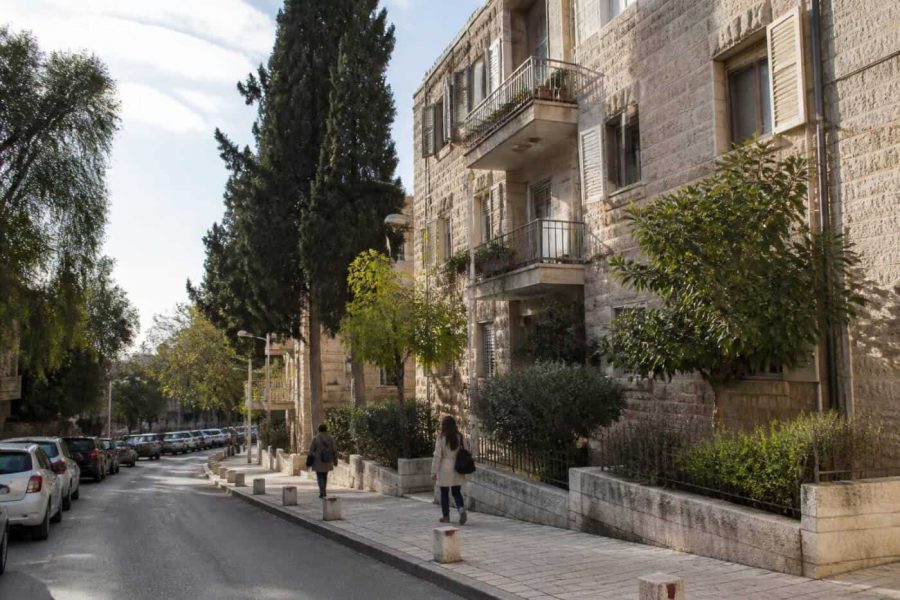 Residential street in Baka, Jerusalem with stone apartment buildings and pedestrians