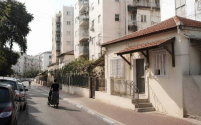 Residential street in Holon with apartment buildings and parked cars on a clear day