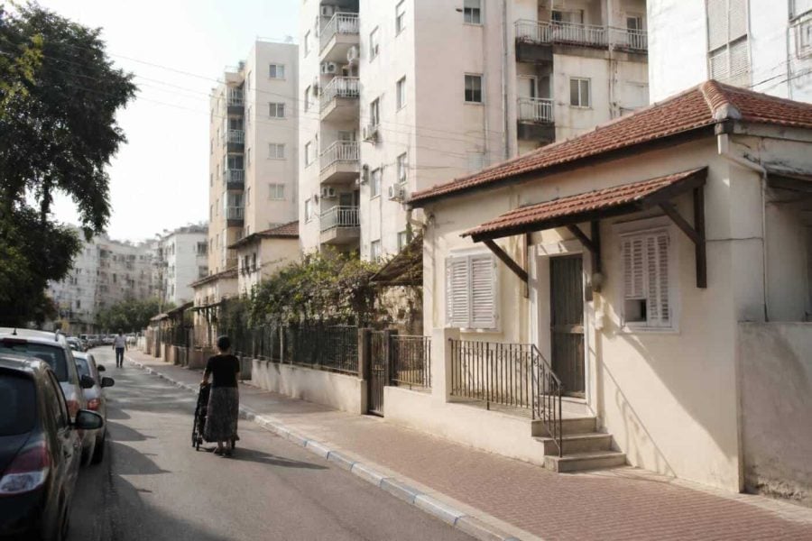 Residential street in Holon with apartment buildings and parked cars on a clear day