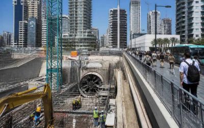 Construction workers and commuters near an urban transit development site in central Israel
