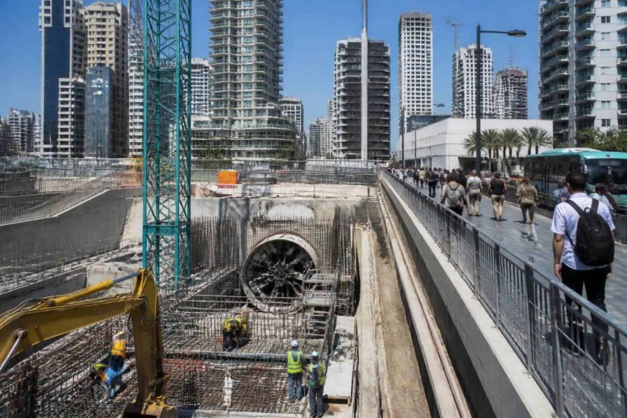 Construction workers and commuters near an urban transit development site in central Israel