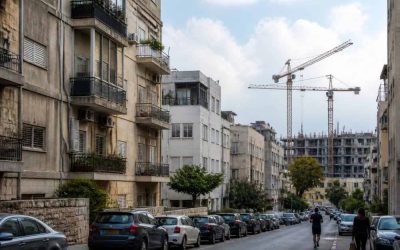 Older apartment buildings on an Israeli residential street with new construction in the background
