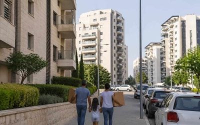Modern apartment buildings in an Israeli residential neighborhood with families walking nearby