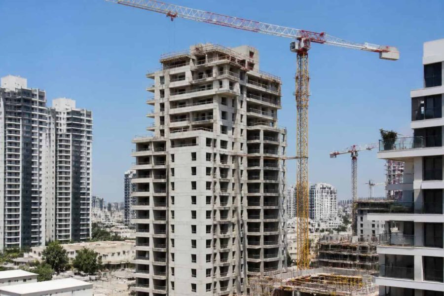 Apartment buildings under construction in an Israeli city with cranes and residential towers