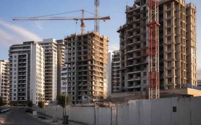 Modern apartment towers under construction in Israel with cranes and a quiet urban street