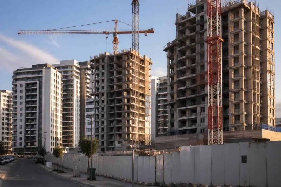 Modern apartment towers under construction in Israel with cranes and a quiet urban street
