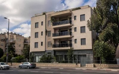 Exterior of a modest apartment building with balconies on a Jerusalem residential street