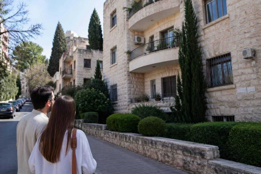 Tree-lined Jerusalem residential street with stone apartment buildings and balconies