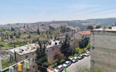 Older stone apartment blocks in Kiryat HaYovel, Jerusalem, with newer homes on the hillside behind them.