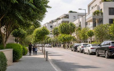 Modern residential street in central Israel with apartment buildings, trees, and family-friendly sidewalks