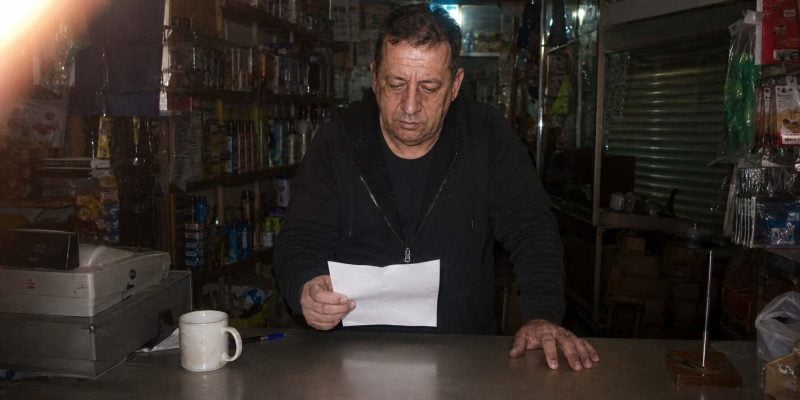 reviewing arnona bill in a cluttered shop