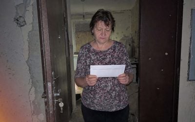 woman receives official letter in war damaged home