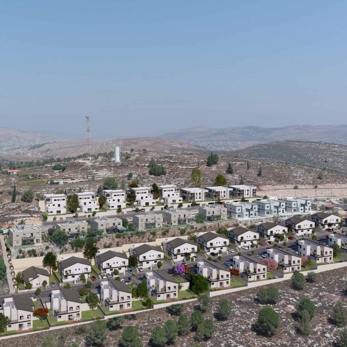 An aerial view of a residential area with rows of white houses, surrounded by hills and mountains, with a radio tower visible in the distance.